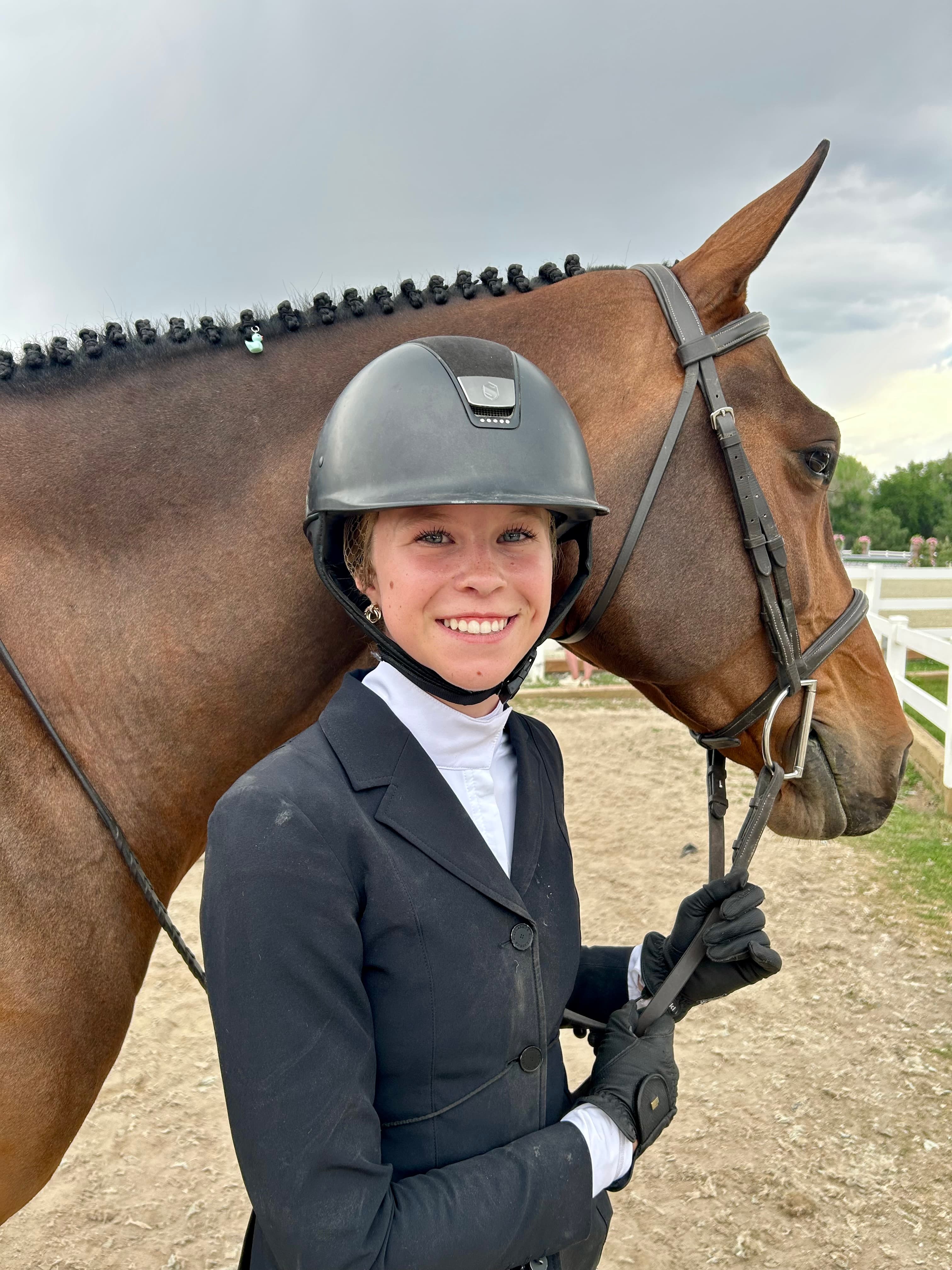 Tully smiling next to her bay horse's head at a show.
