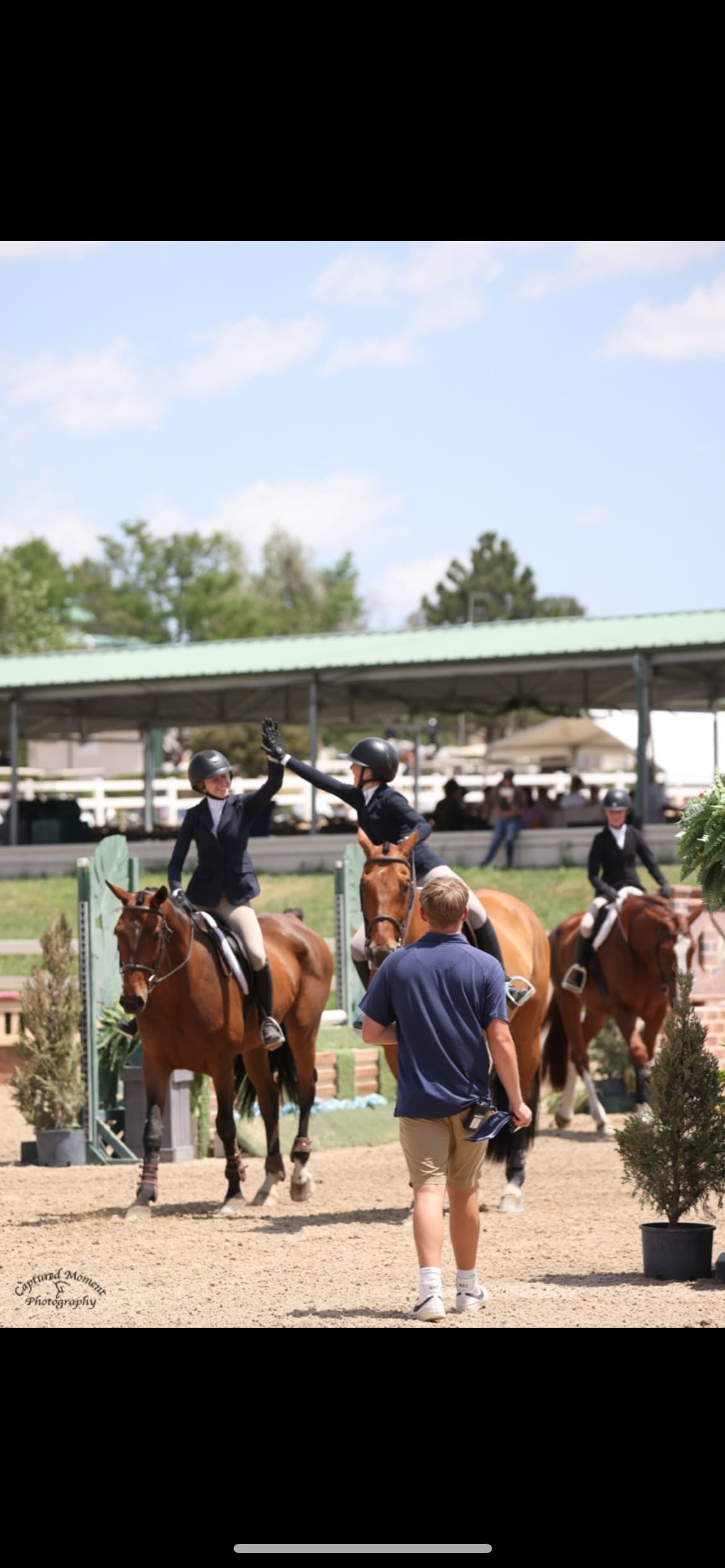 Tully high-fiving a fellow rider from horseback after a round.